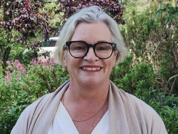 Staff portrait of the principal in a garden.