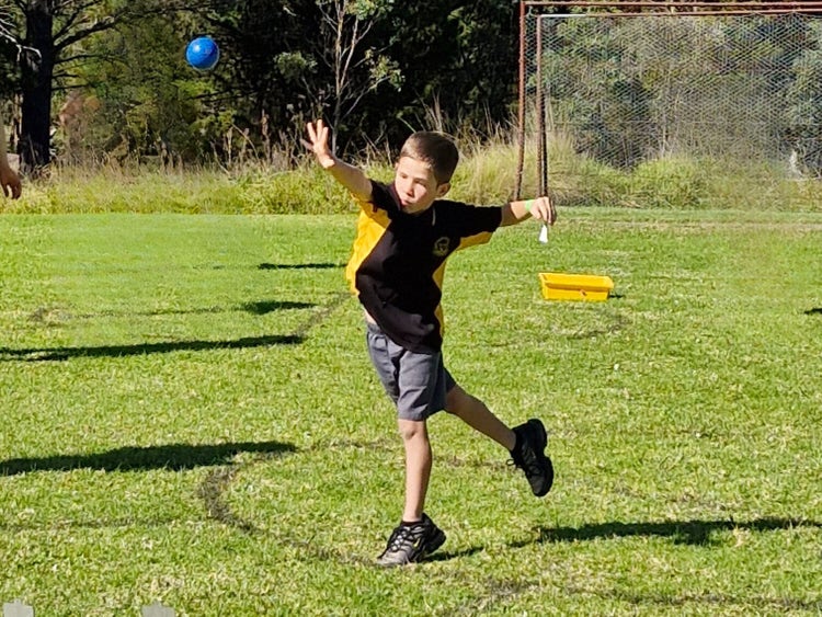 A boy does a shot put throw.