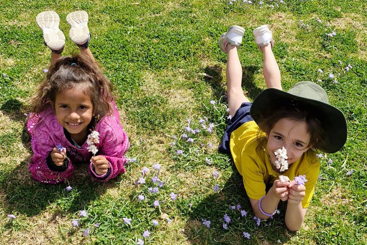 Two girls lying in the playground holding flowers.