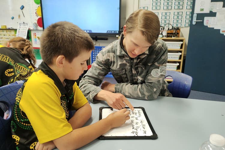 A School Learning Support Officer works with a student.
